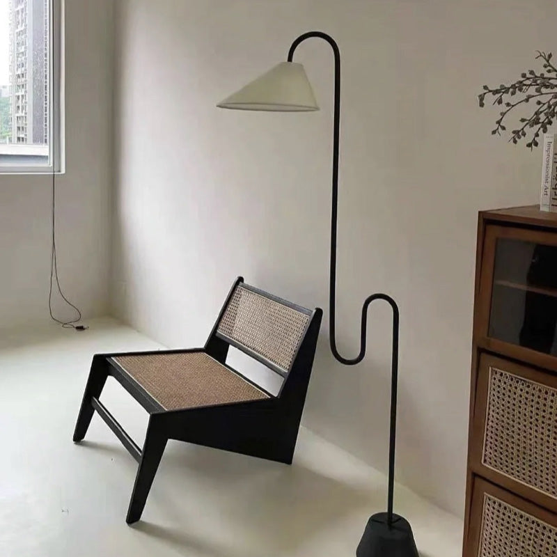 Modern floor lamp with a unique design next to a chair in a minimalistic room.