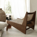 Wooden lounge chair with woven backrest in a room with light curtains and decor items.