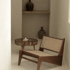 Wooden chair with wicker backrest and a small round wooden table in a minimalistic room.