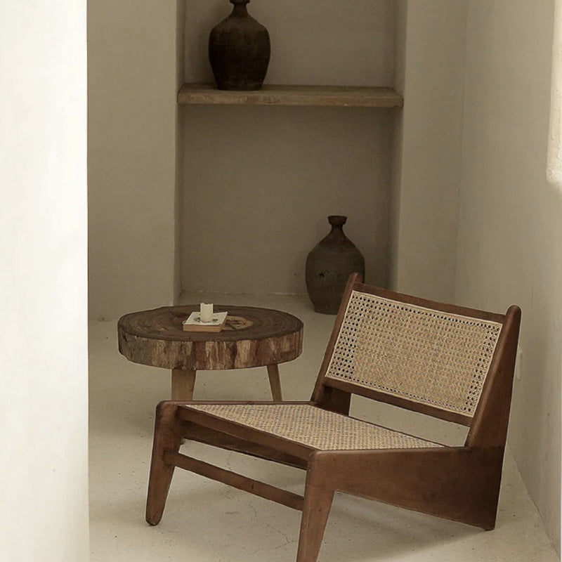 Wooden chair with wicker backrest and a small round wooden table in a minimalistic room.