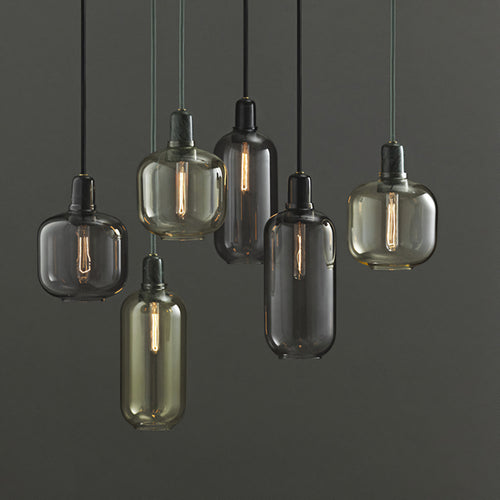 Six hanging pendant light fixtures with translucent smoked glass shades in smoky gray, amber, and dark charcoal tones, suspended against a dark gray background.
