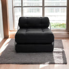 A black tufted modular sofa bed or daybed with a thick cushioned seat and back, supported by slim metal legs, placed on a gray shag rug in a sunlit room with a large window and wooden floor.
