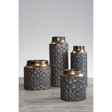 Set of four textured metal vases on a gray surface with a light gray background