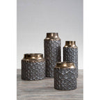 Set of four textured metal vases on a gray surface with a light gray background