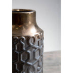 Bronze-colored vase with geometric pattern on a neutral background