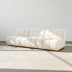 Modern white sofa in a minimalistic room with a light gray floor and white walls.