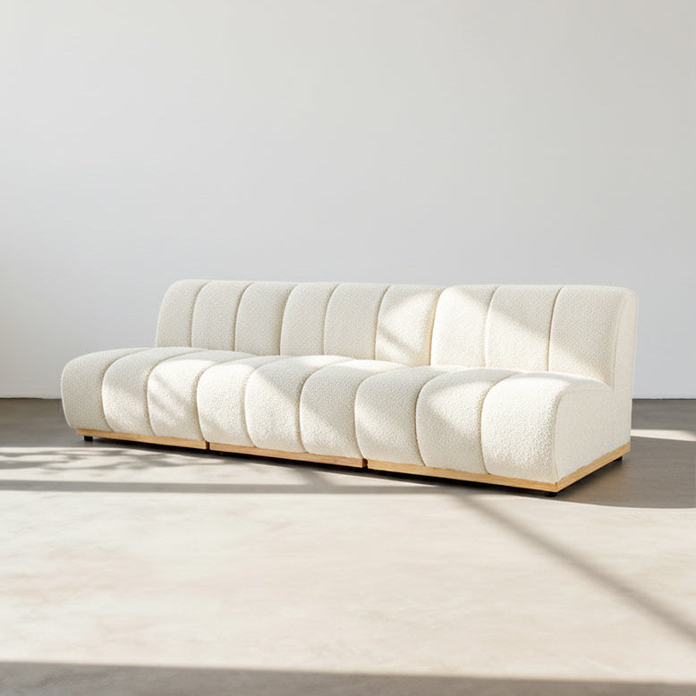 Modern white sofa in a minimalistic room with a light gray floor and white walls.