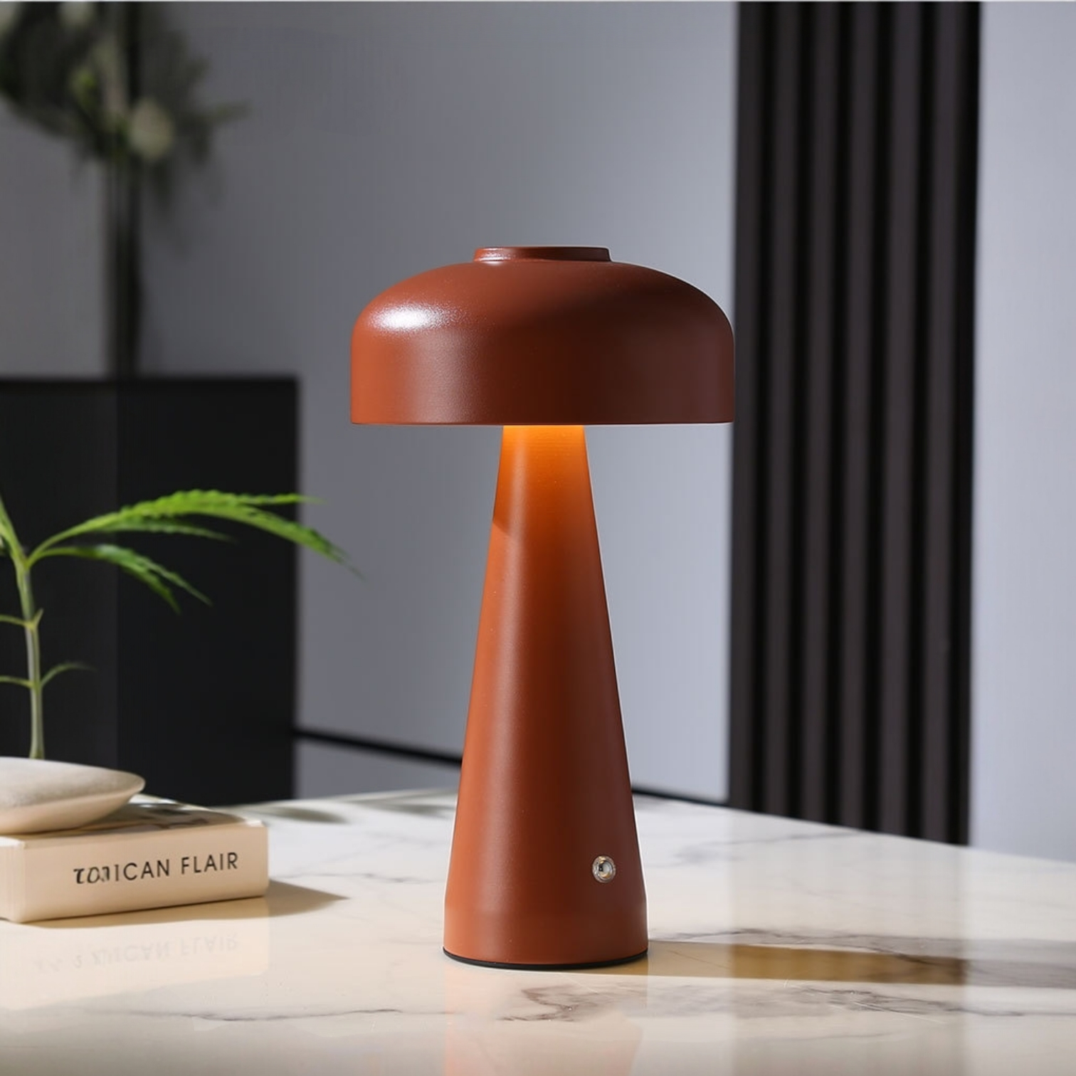 Brown table lamp on a marble surface with books and a plant in the background