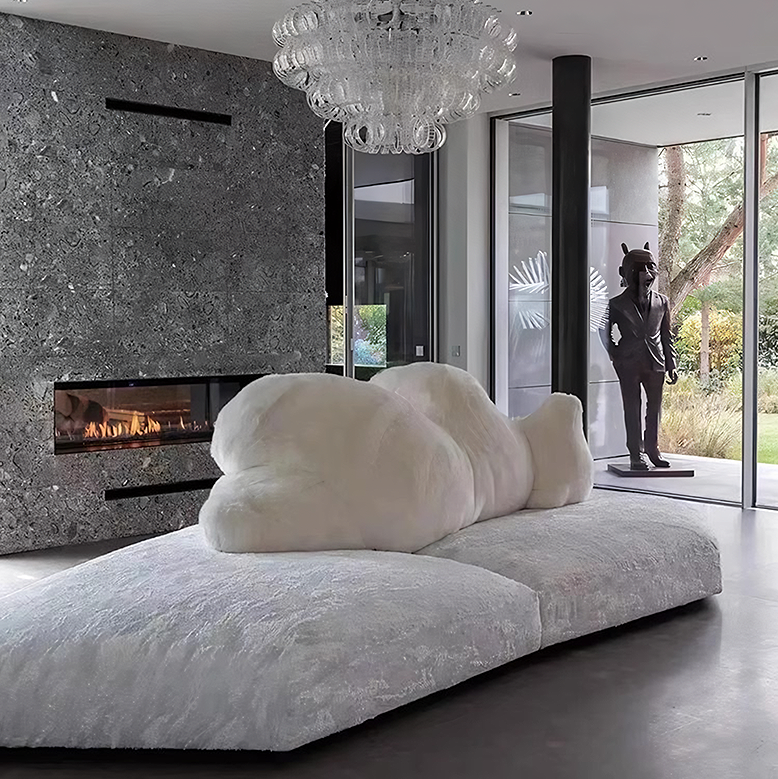 Modern living room with a large white cloud-shaped pillow on a sofa, a fireplace, and a chandelier.