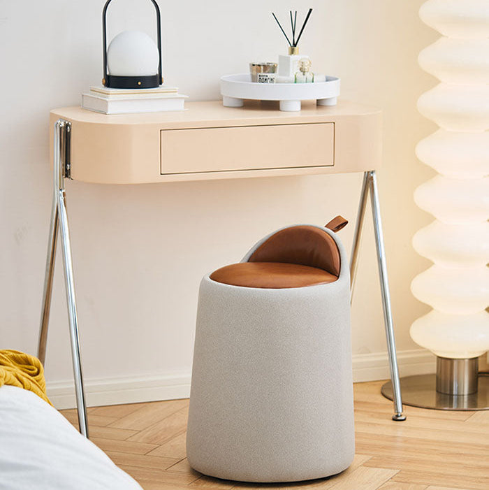 Small round stool with a brown cushion in front of a light wooden desk.