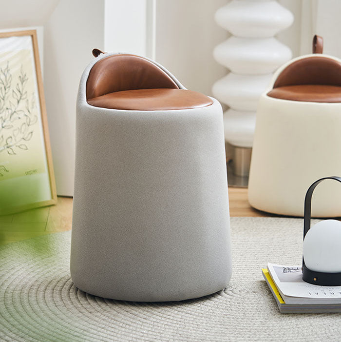 Small round stool with a brown cushioned top in a room setting.