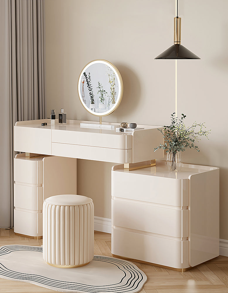 Modern white vanity with round mirror, stool, and decorative elements in a room.