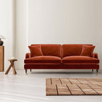 Red sofa in a minimalistic living room with a wooden side table and rug.