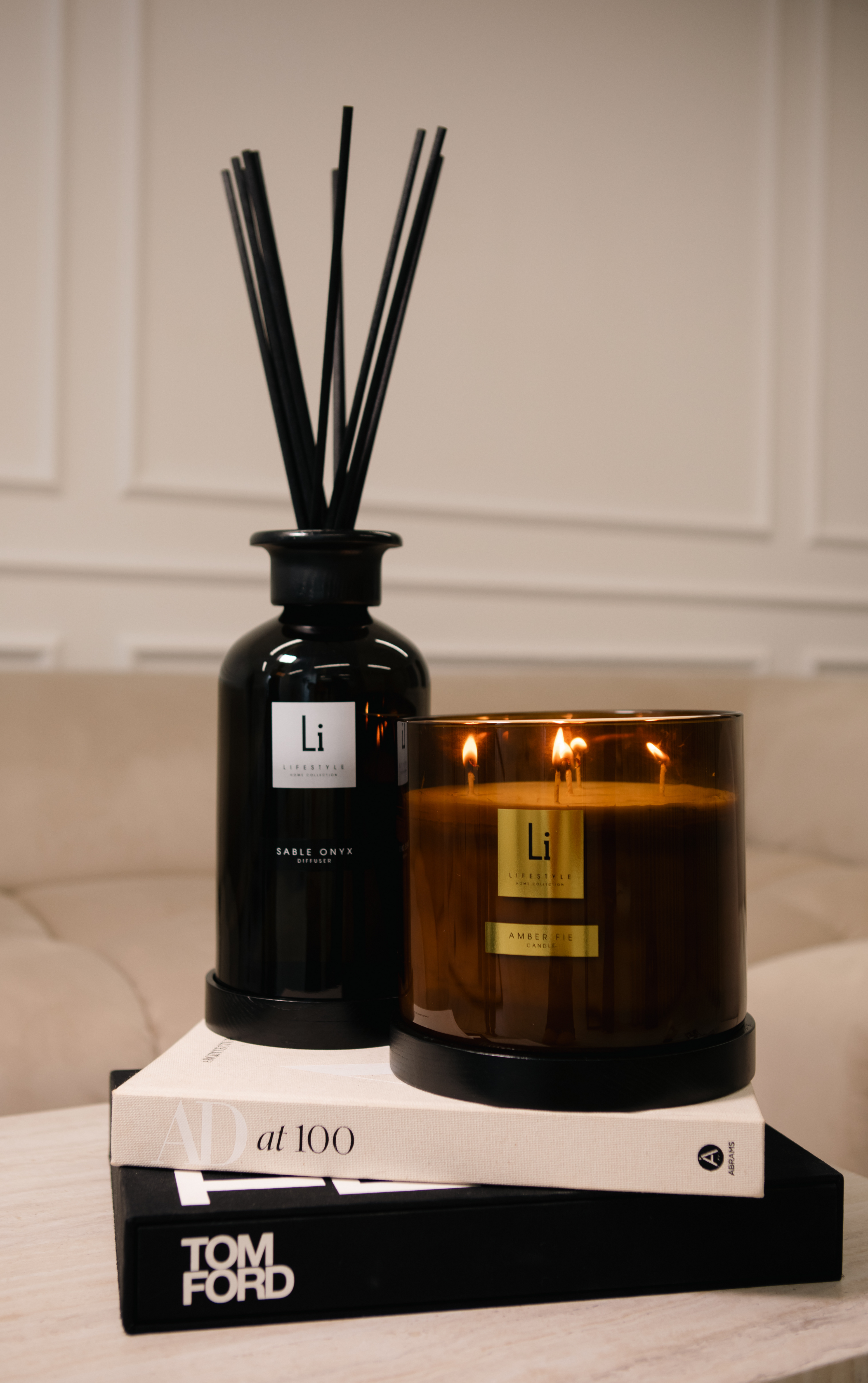 Candle and diffuser set on books with 'Li' branding against a neutral background