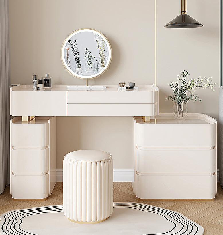 Modern white vanity desk with round mirror, drawers, and stool in a stylish room.