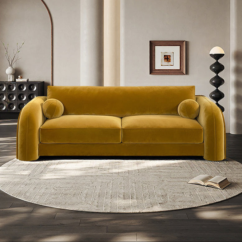 Mustard yellow sofa in a modern living room with a gray rug and decorative items.