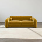 Mustard yellow sofa in a minimalistic room with a white wall and light wood floor.