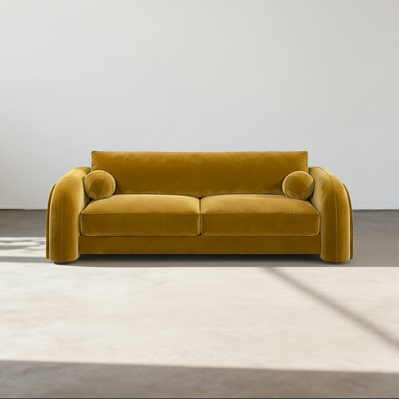 Mustard yellow sofa in a minimalistic room with a white wall and light wood floor.