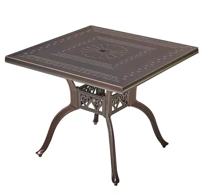 Bronze-colored outdoor table with intricate design on a white background
