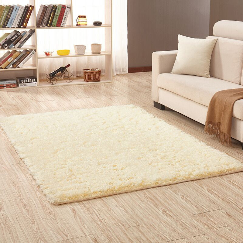 Beige rug on a wooden floor with a white sofa and bookshelf in the background