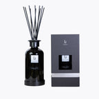 Black diffuser bottle with reeds and packaging on a white background