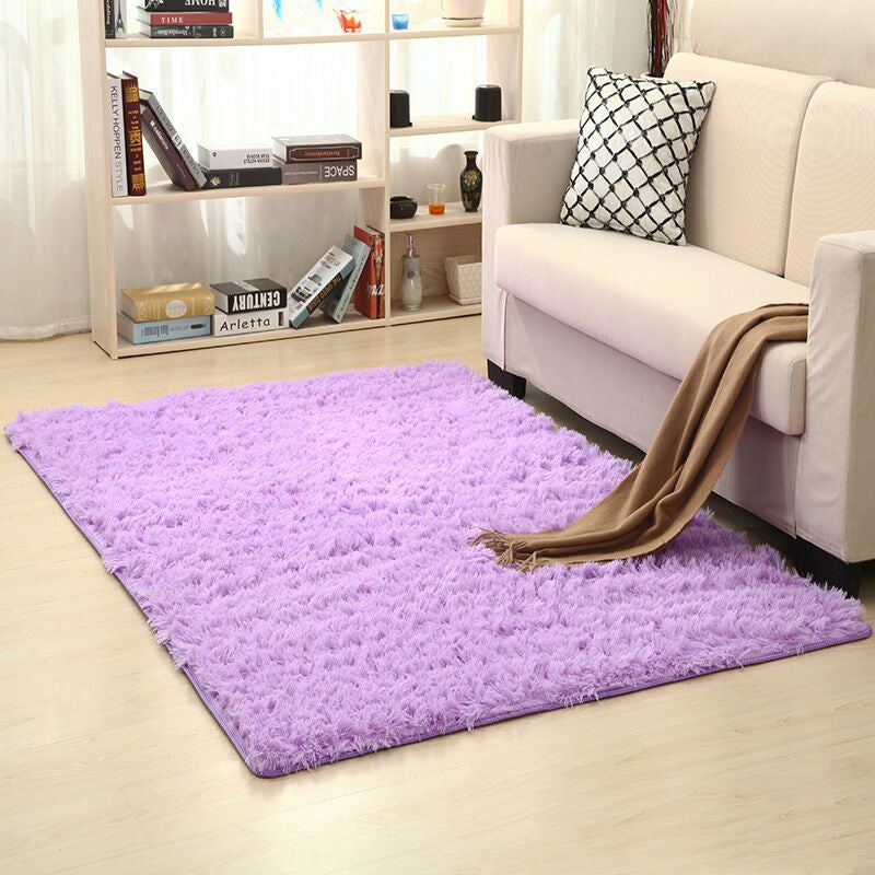 Living room with a purple rug, white sofa, and bookshelf.