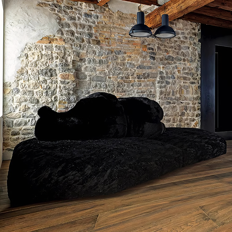 Black sofa against a stone wall with wooden beams
