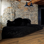 Black sofa against a stone wall with wooden beams