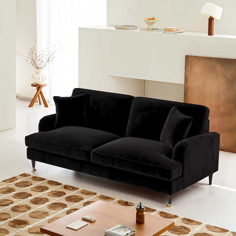 Black sofa in a living room with a wooden coffee table and decorative items.