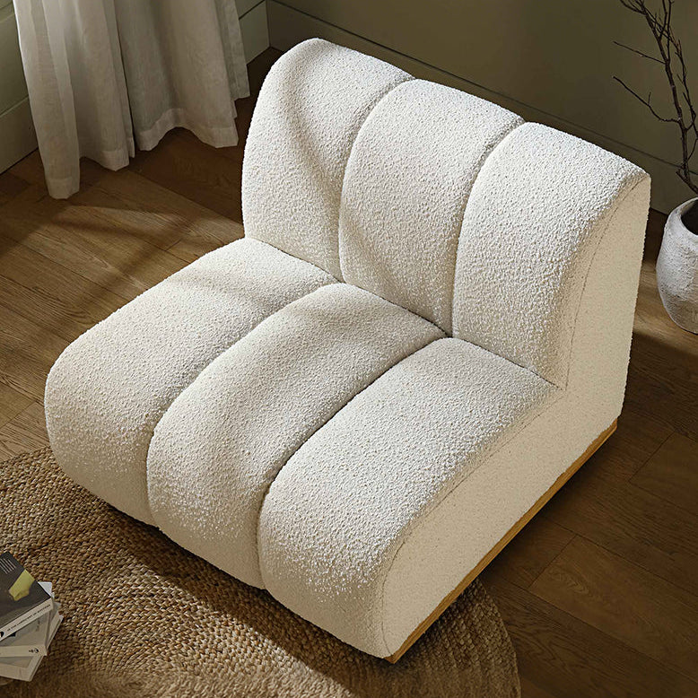 White plush armchair in a room with a plant and curtains