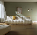 White textured sofa with a yellow pillow in a room with a lamp and framed picture on the wall.