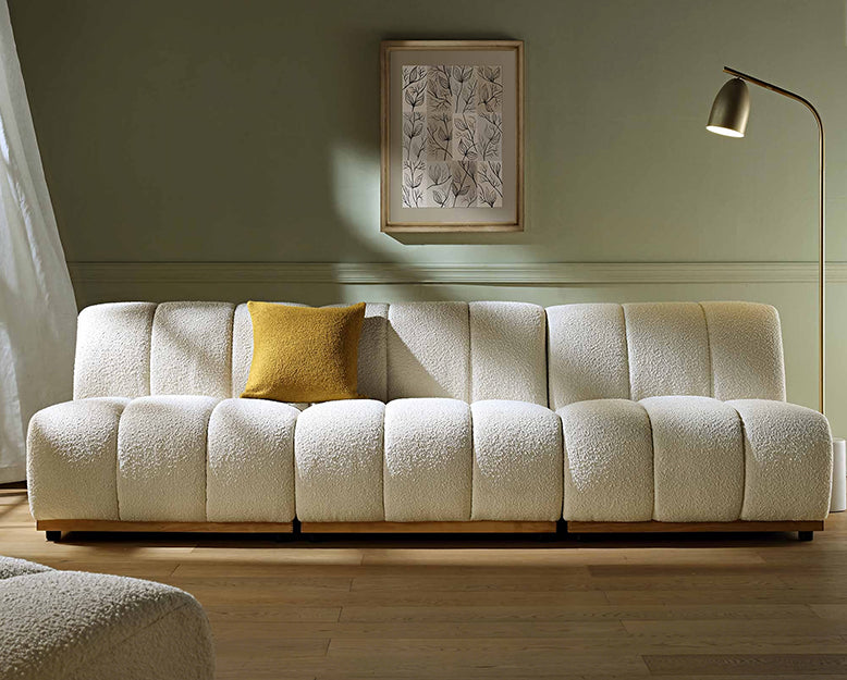 White textured sofa with a yellow pillow in a room with a lamp and framed picture on the wall.