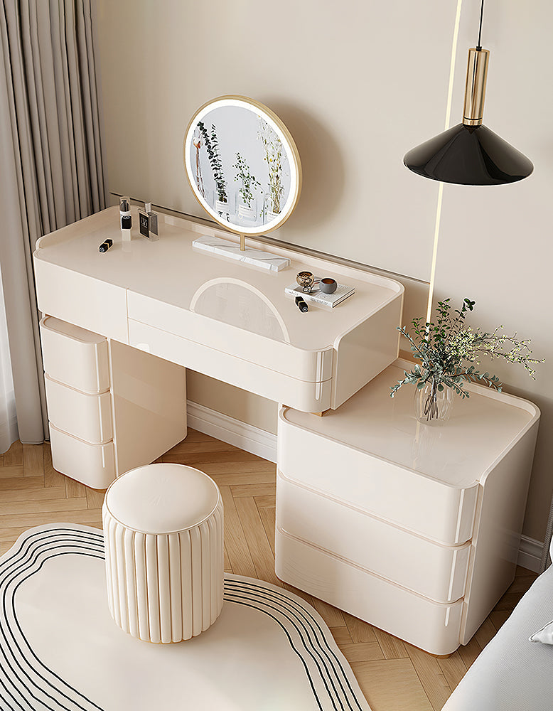 Beige vanity table with mirror, stool, and decorative items in a room.