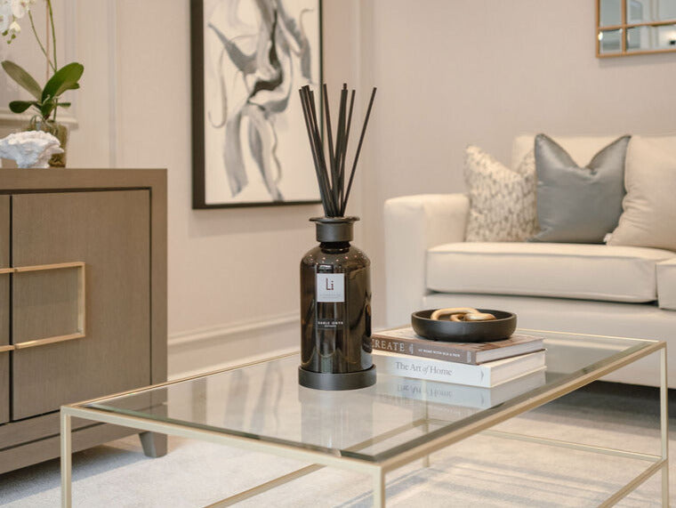 Living room with a glass coffee table, decorative vase, and books.