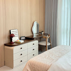 Dressing table with mirror and chair next to a bed in a bedroom.