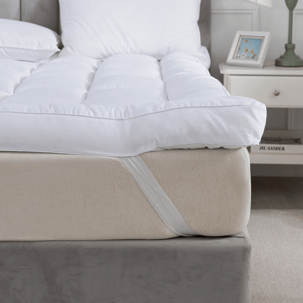 White comforter on a beige bed with a nightstand in the background