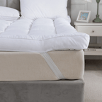 White comforter on a beige bed with a nightstand in the background