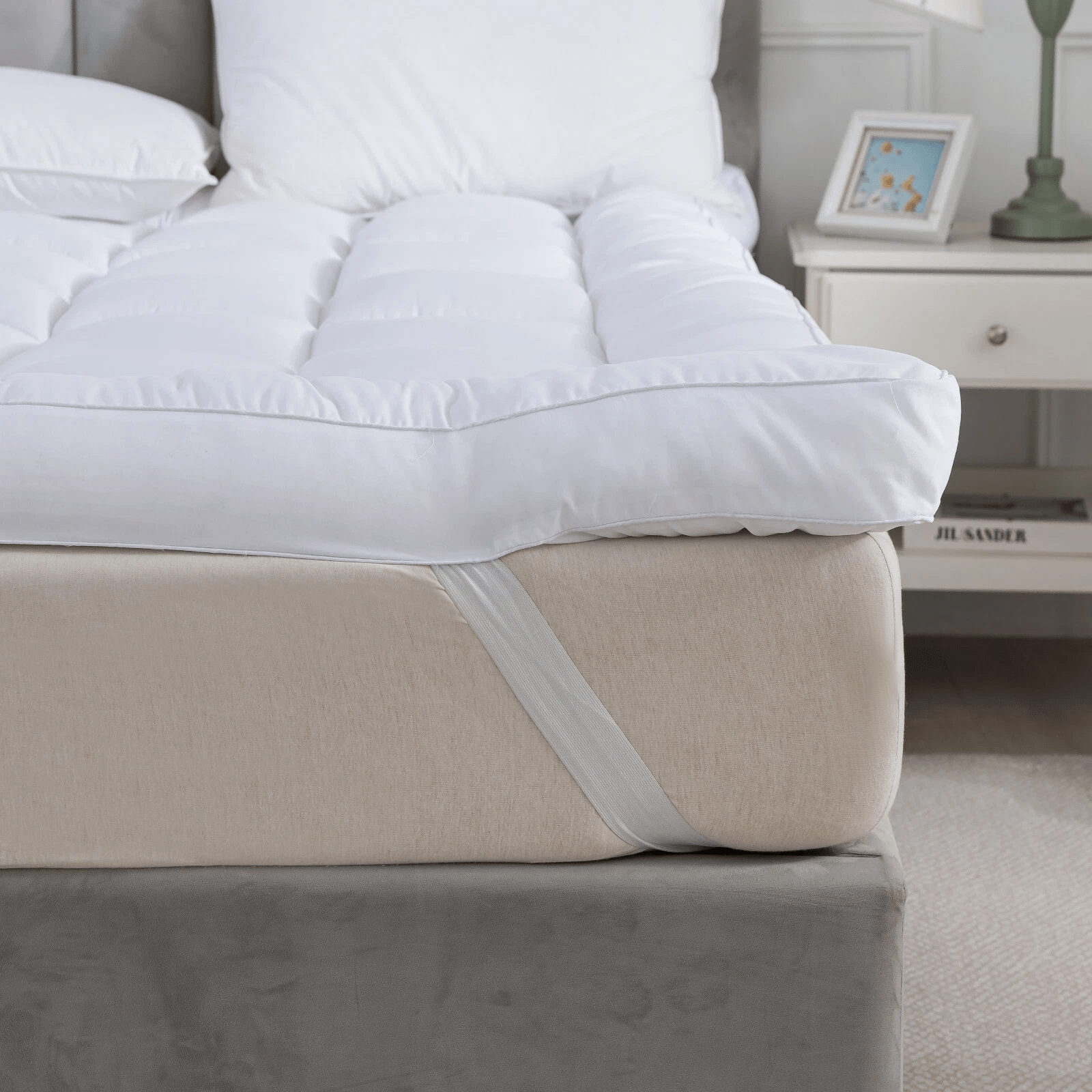 White comforter on a beige bed with a nightstand in the background