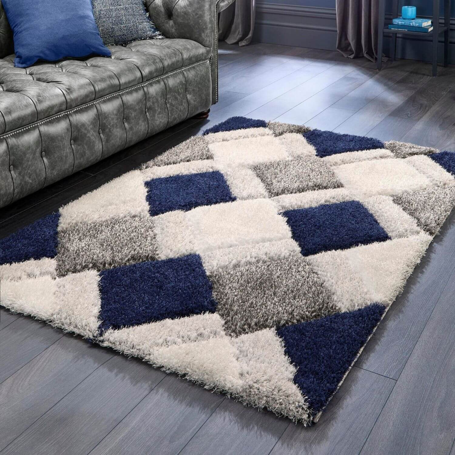 Checkered area rug with blue, gray, and white squares on a wooden floor.