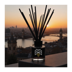 Diffuser with sticks against a sunset cityscape background