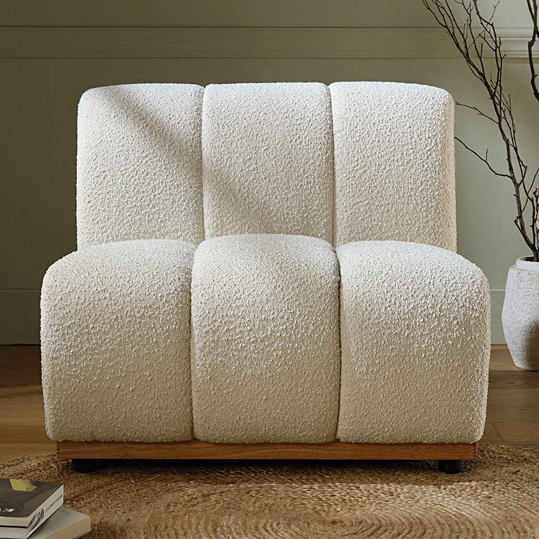 White textured armchair in a room with a plant and books on a shelf.
