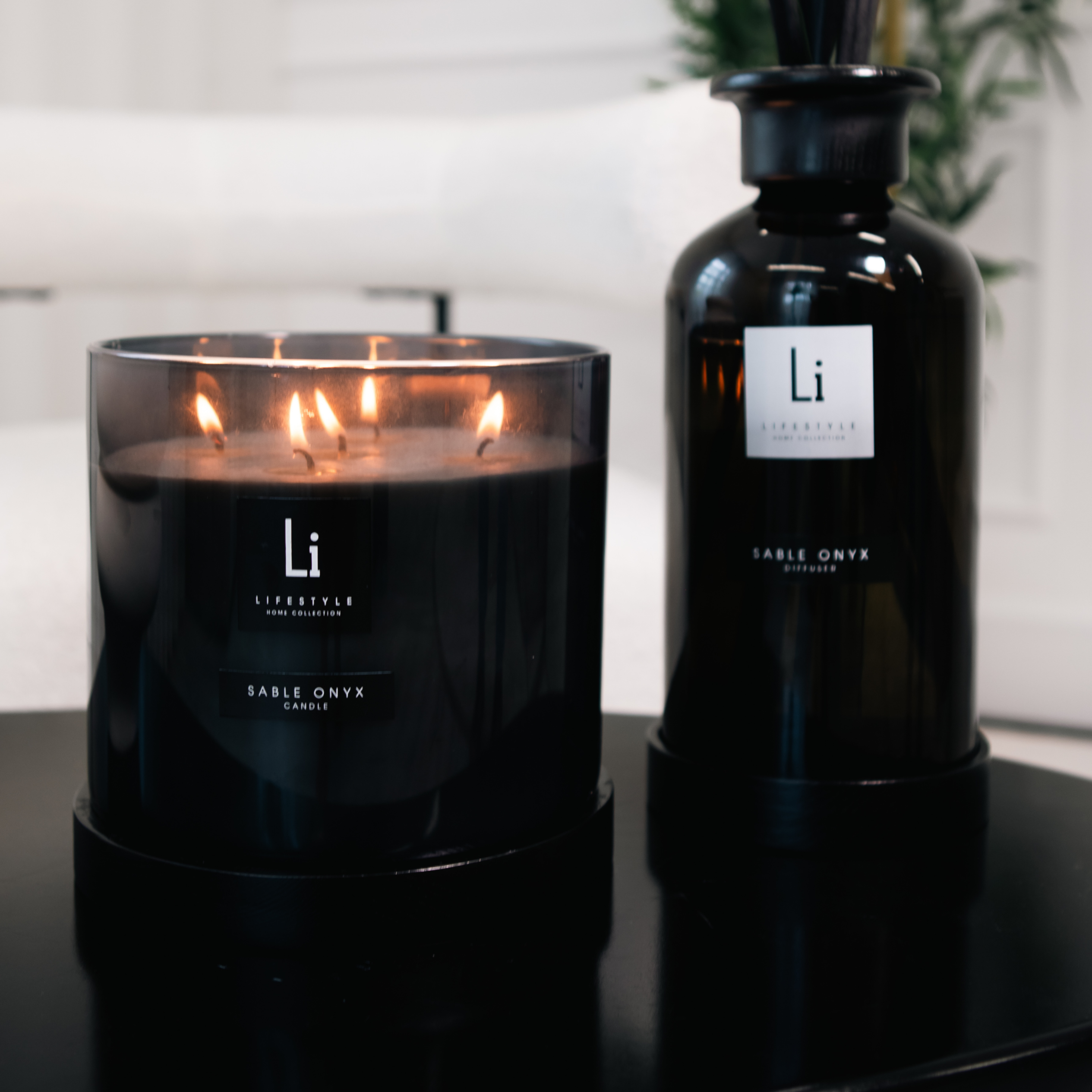 Black candle and bottle with 'Li' branding on a reflective surface.