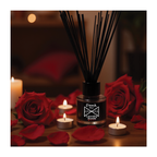 Diffuser with black sticks surrounded by red roses and candles on a dark background