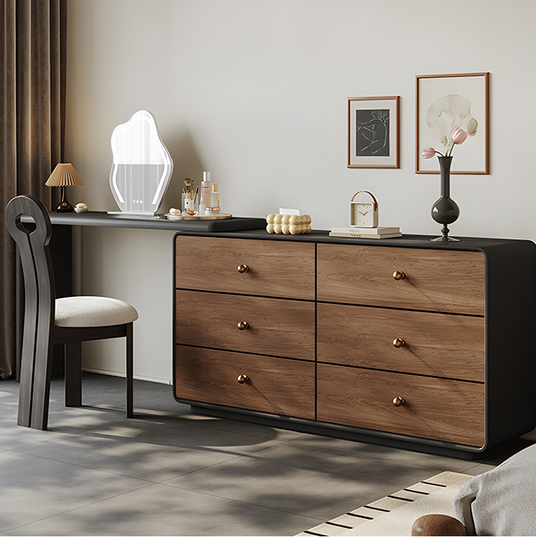 Wooden dresser with black top in a room with a chair and decor items.