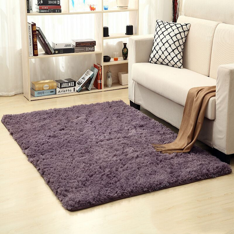 Living room with a purple rug, white sofa, and bookshelf.