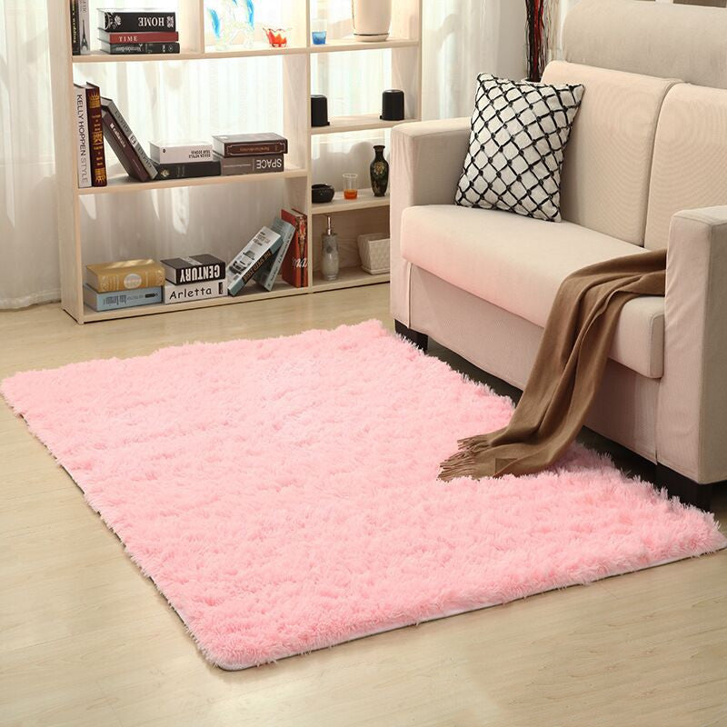 Living room with a pink rug, beige sofa, and bookshelf.