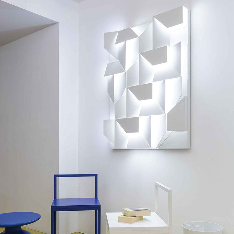 Modern room interior with geometric wall light fixture, blue chair, and white table.