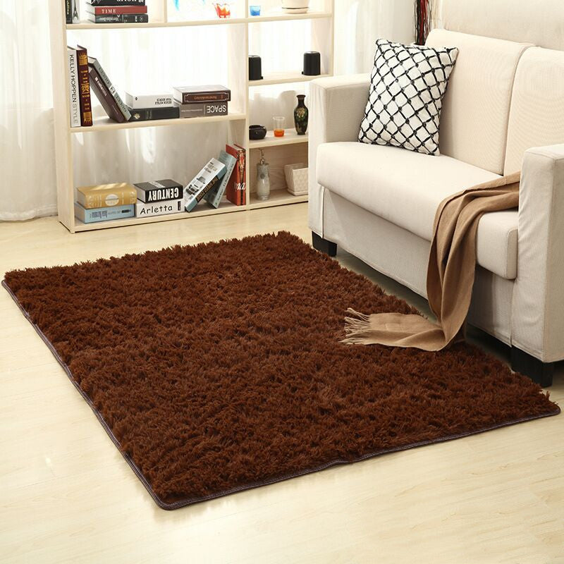 Brown rug on a light wood floor in a living room setting with a white sofa and bookshelf.