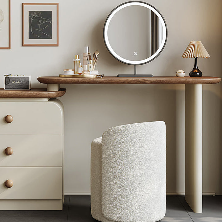 Wooden vanity table with round mirror, lamp, and decorative items in a room setting.