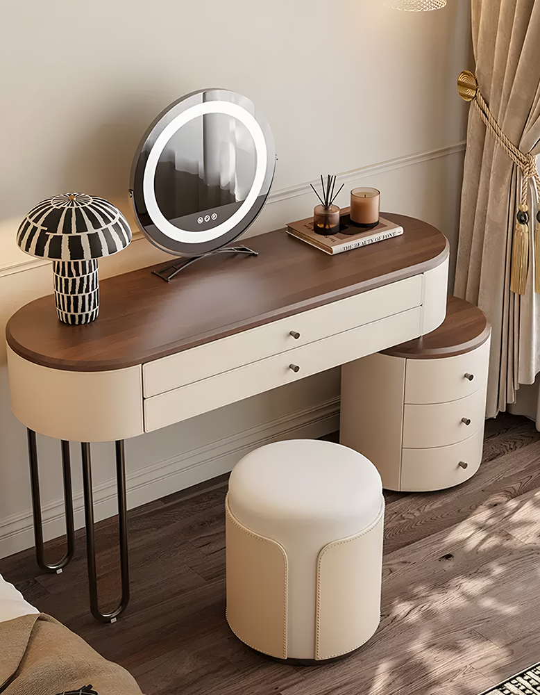 Dressing table with illuminated mirror, drawers, and a stool in a room setting.